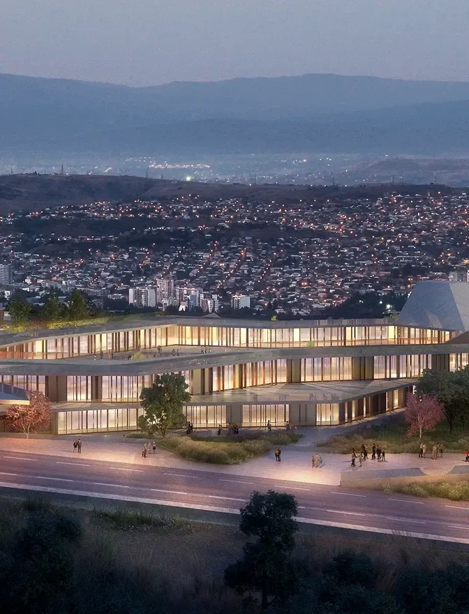A large Mira Verde building lit at dusk against the lights of Tbilisi